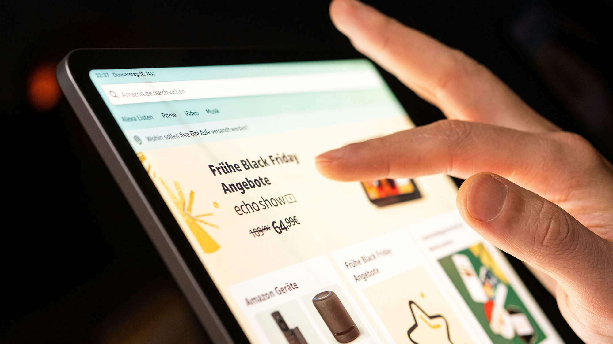 Eine Person tippt mit dem Finger auf ein Tablet, auf dem ein Online-Shop mit Werbung für den Black Friday geöffnet ist.