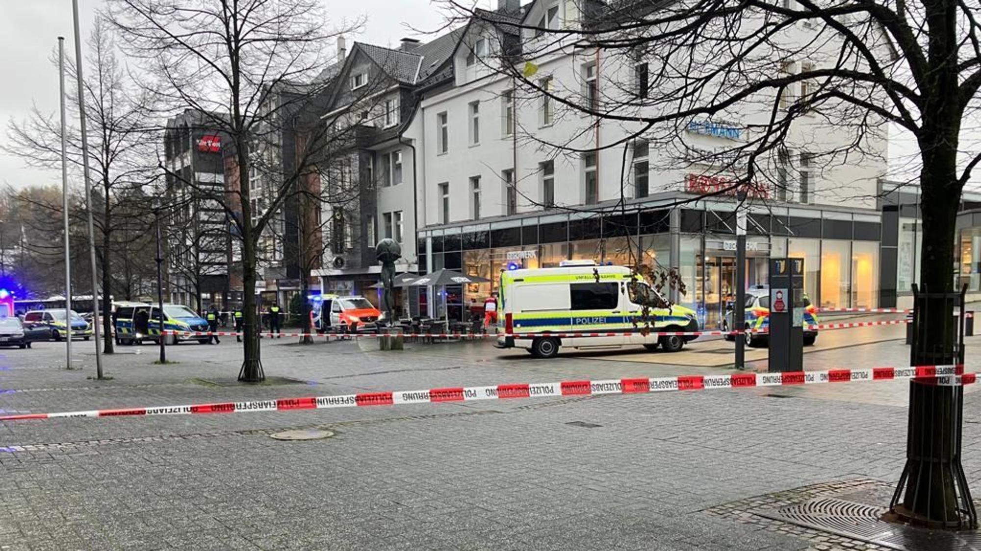 Polizeiautos und Absperrband vor einem Tatort in einer Fußgängerzone.