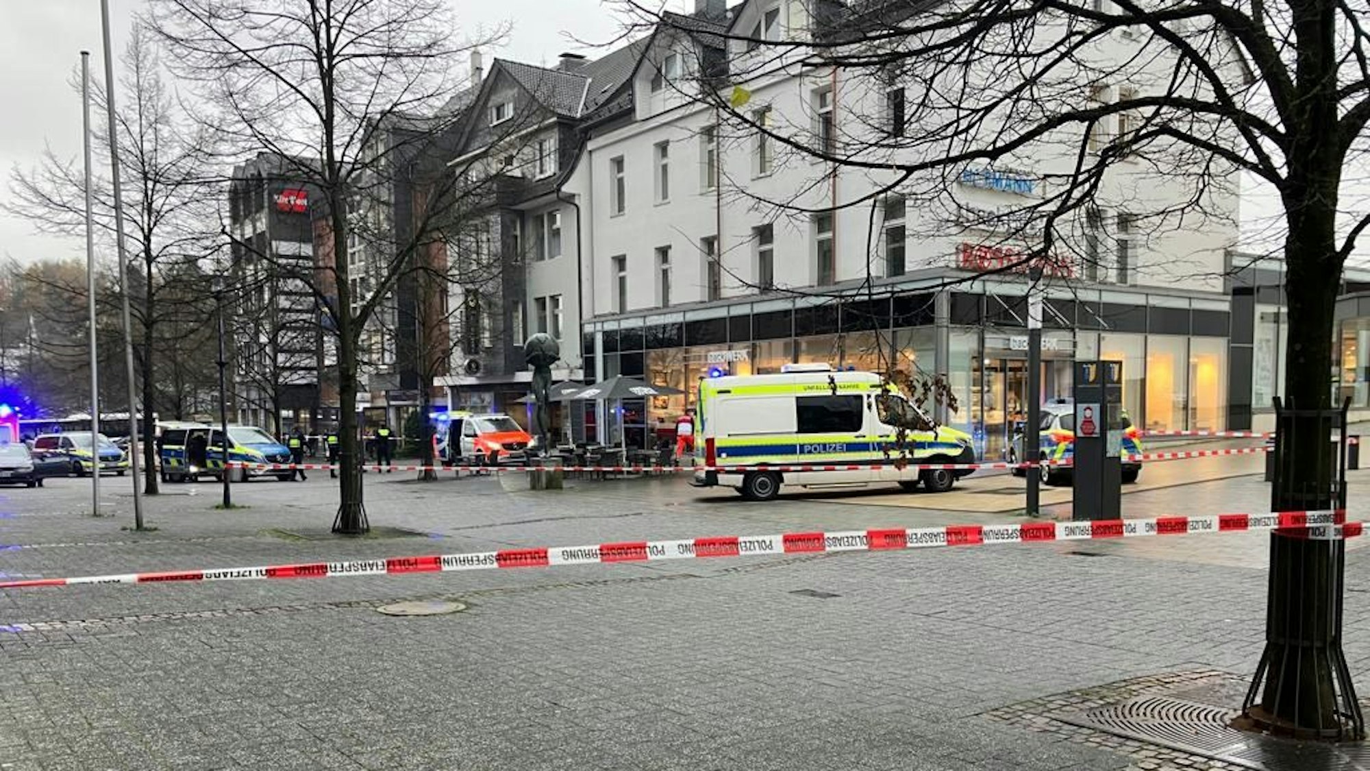 Polizeiautos und Absperrband vor einem Tatort in einer Fußgängerzone.