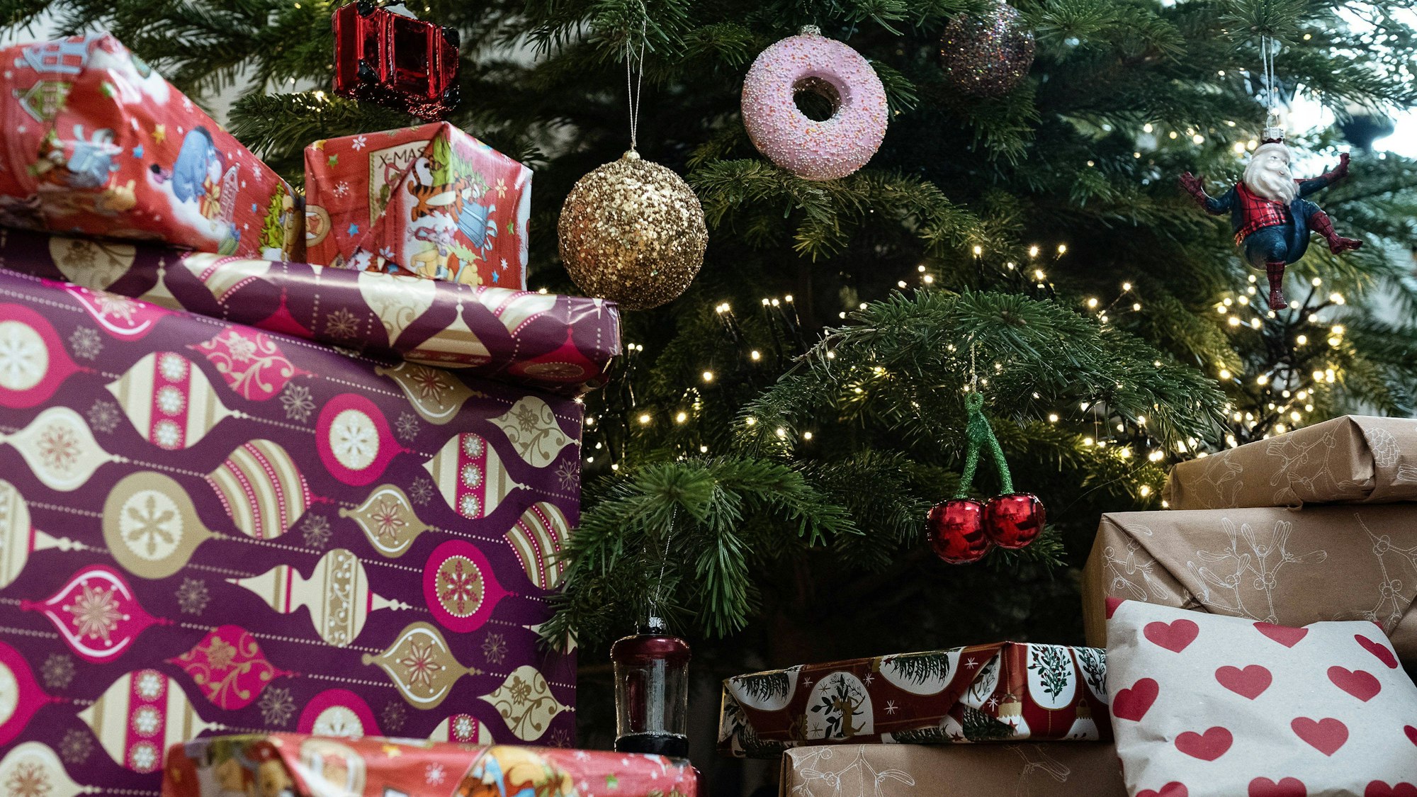 Eingepackte Geschenke liegen unter einem geschmückten Weihnachtsbaum.