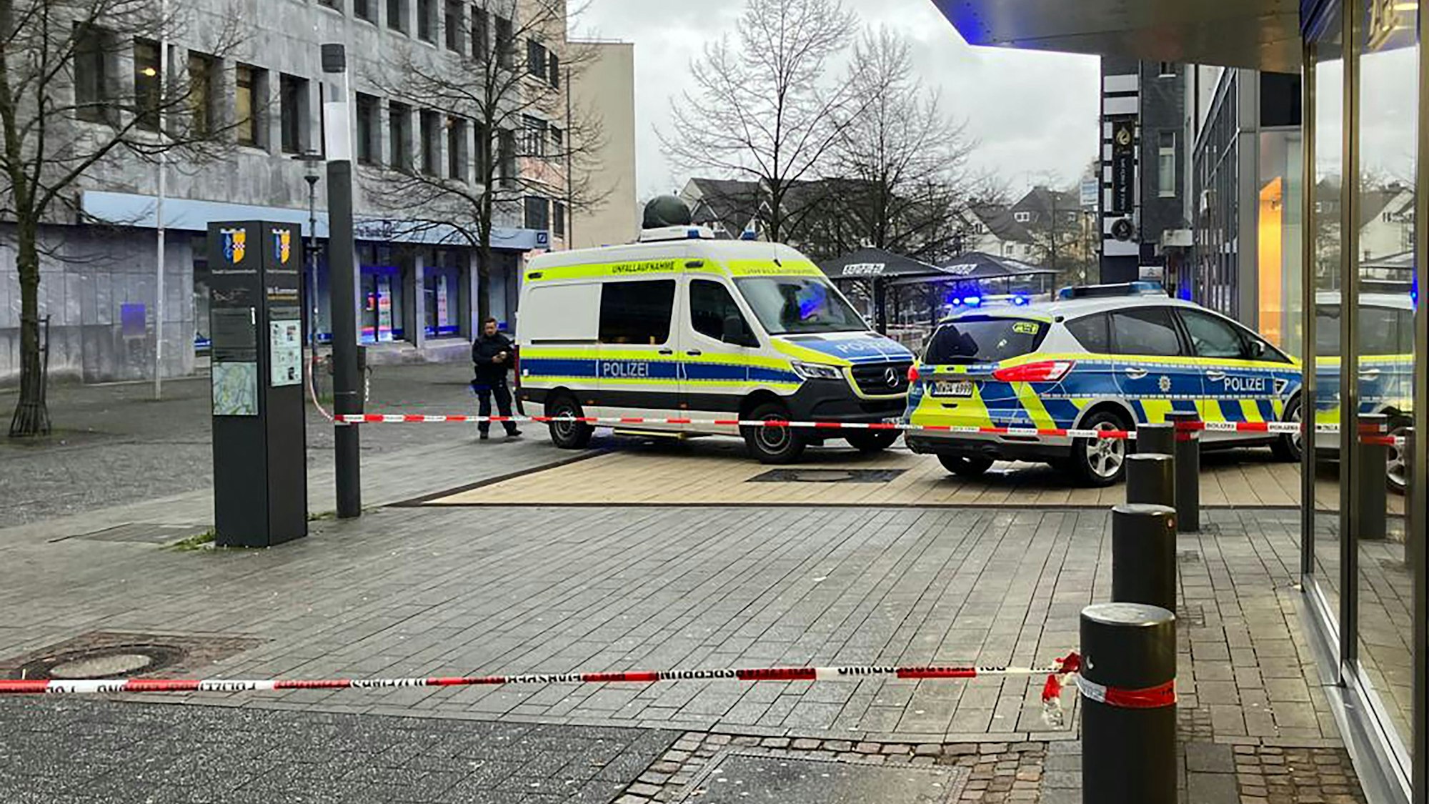 Zwei Polizeiautos stehen auf einer Fußgängerzone. Es ist Absperrband zu sehen.