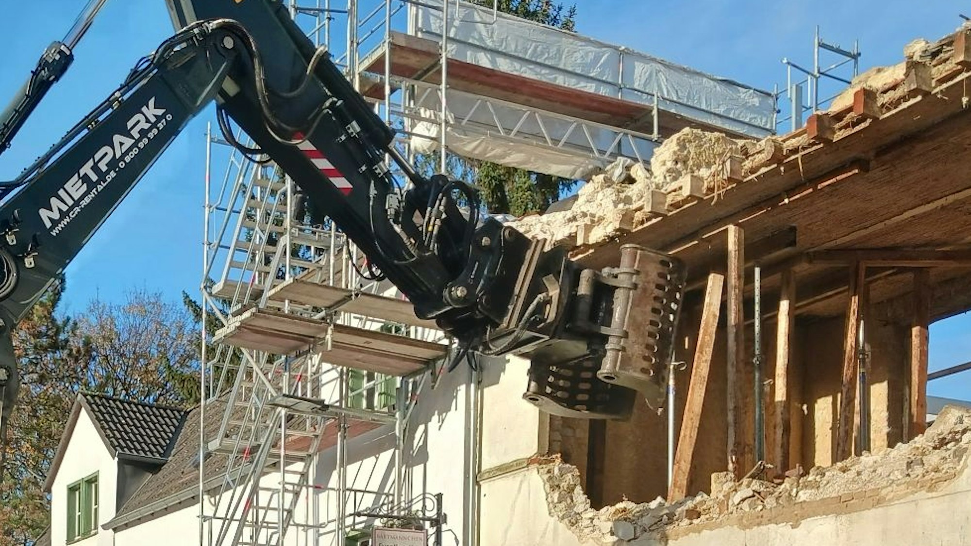 Ein Bagger reißt ein altes Haus ab.