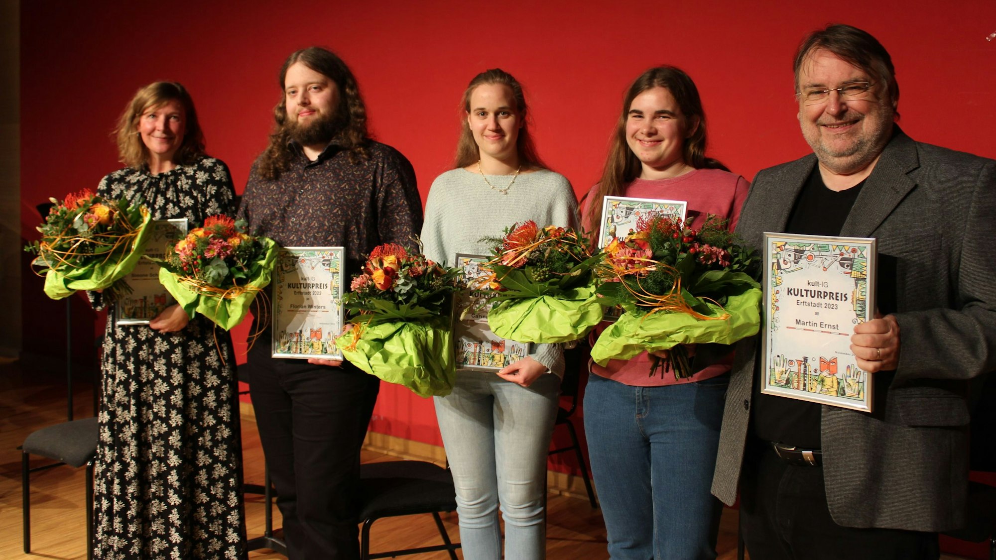 Zu sehen sind die Preisträger, die auf einer Bühne stehen.