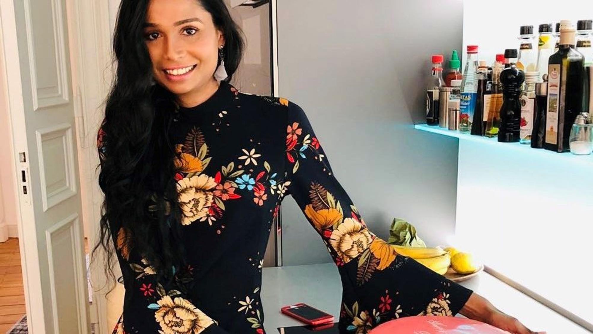 Eine Frau steht mit einer Torte in ihrer Küche