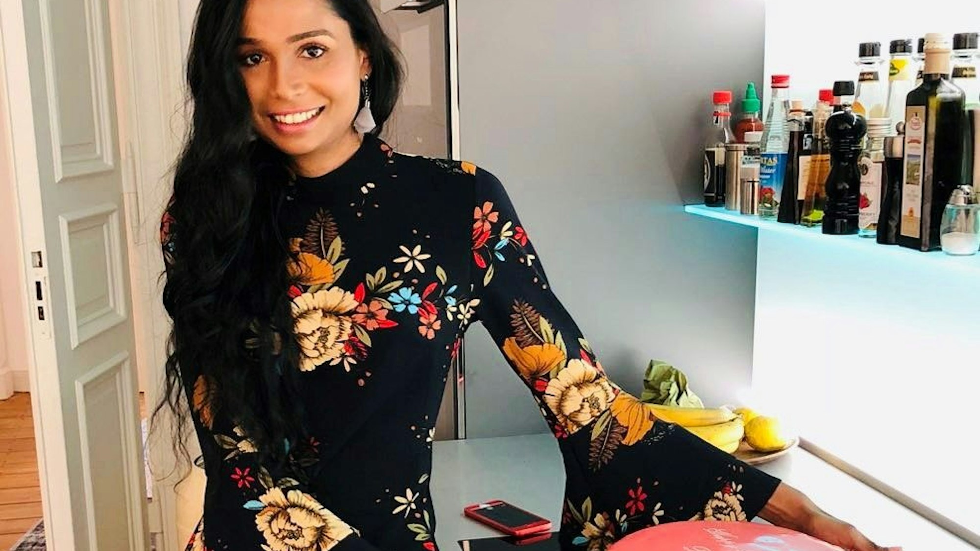 Eine Frau steht mit einer Torte in ihrer Küche