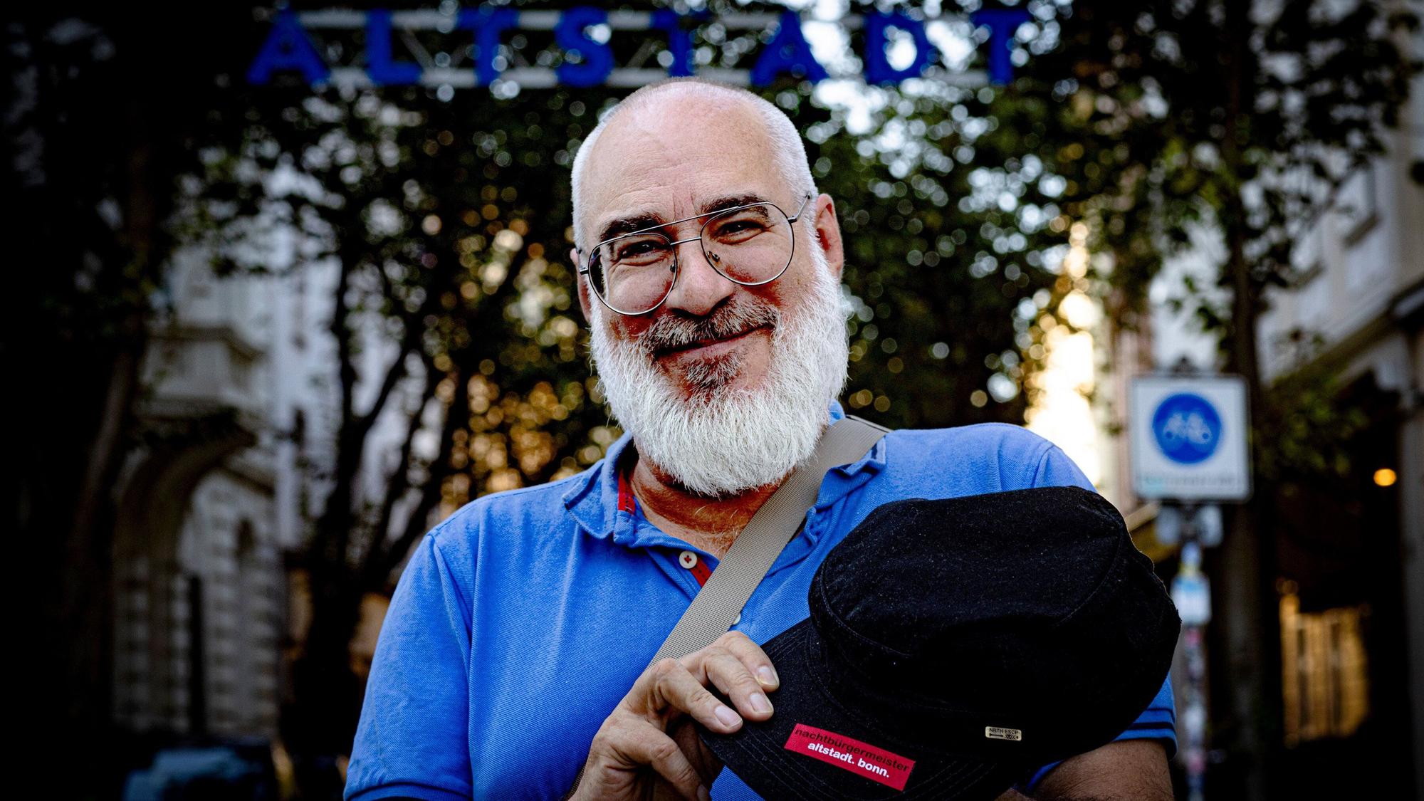 Vor dem Tor der BonnerAltstadt ist Nachtbürgermeister Achim Kettemer im Porträt zu sehen. Er trägt ein blaues Polohemd.