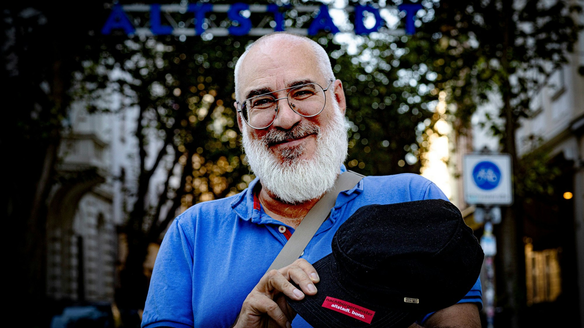 Vor dem Tor der BonnerAltstadt ist Nachtbürgermeister Achim Kettemer im Porträt zu sehen. Er trägt ein blaues Polohemd.