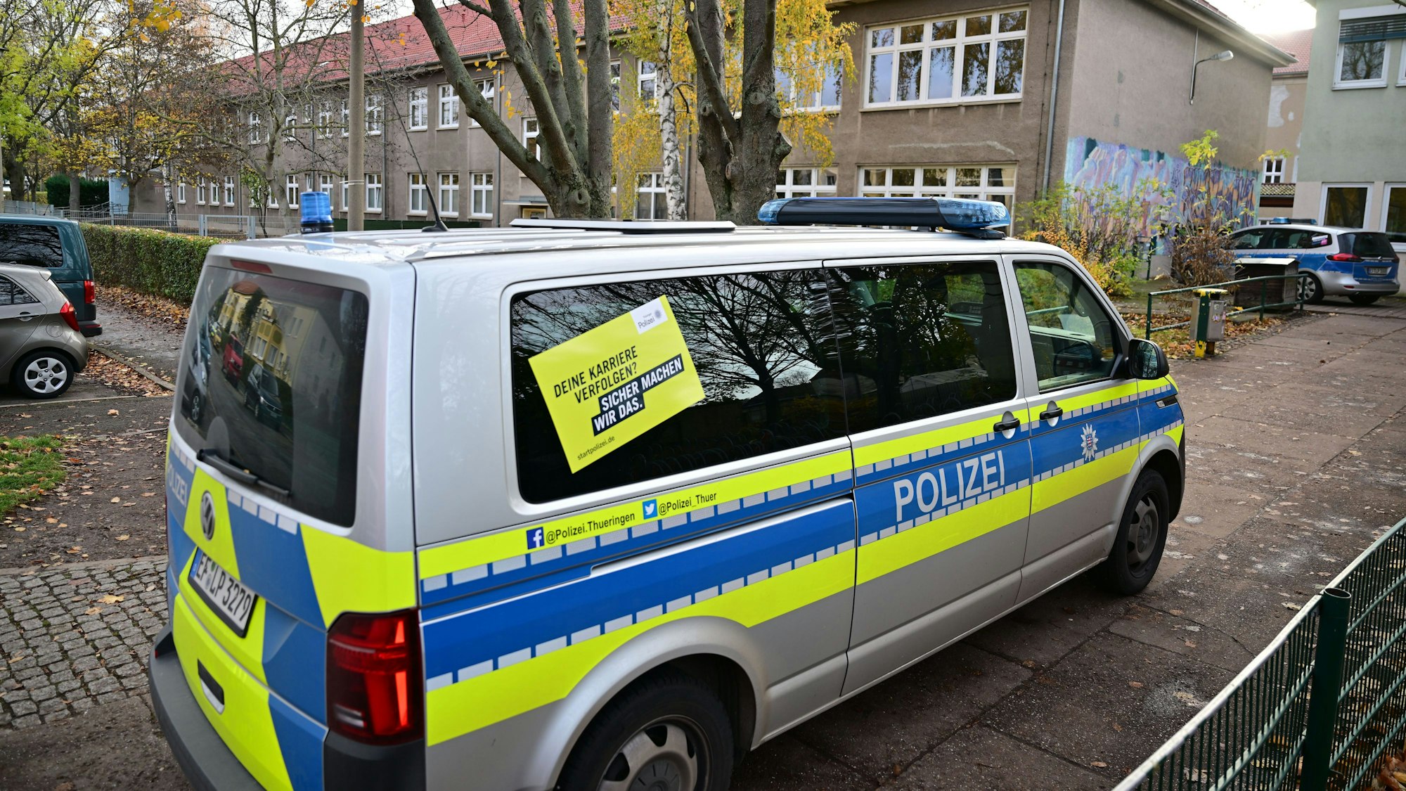 17.11.2023, Thüringen, Erfurt: Polizeifahrzeuge stehen vor der Erfurter Grundschule am Schwemmbach. Nach Drohungen überprüft die Polizei zwei Erfurter Schulen. An den Schulen sind nach Angaben der Polizei Mails mit Bombendrohungen eingegangen. Foto: Martin Schutt/dpa +++ dpa-Bildfunk +++