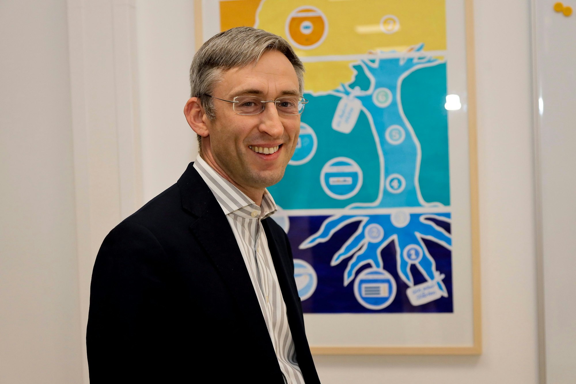 Der Schulleiter steht vor einem Plakat in der neuen Schule-