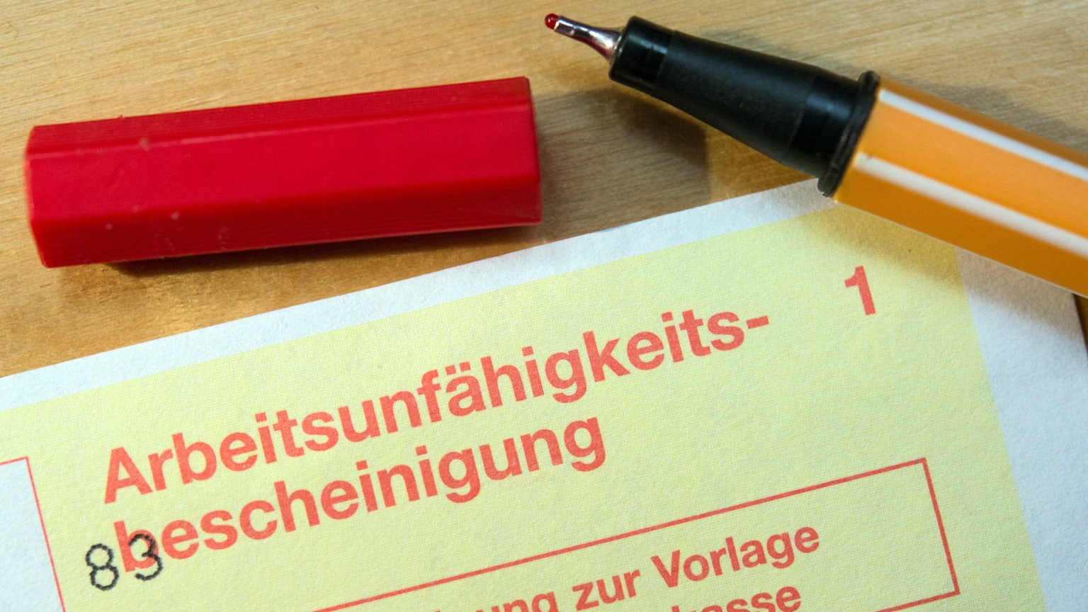 Eine Arbeitsunfähigkeitsbescheinigung liegt auf einem Tisch.