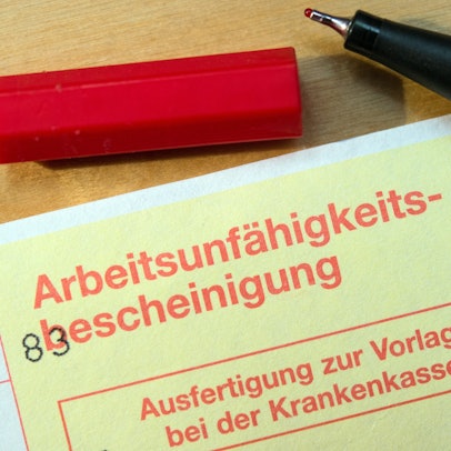 Eine Arbeitsunfähigkeitsbescheinigung liegt auf einem Tisch.