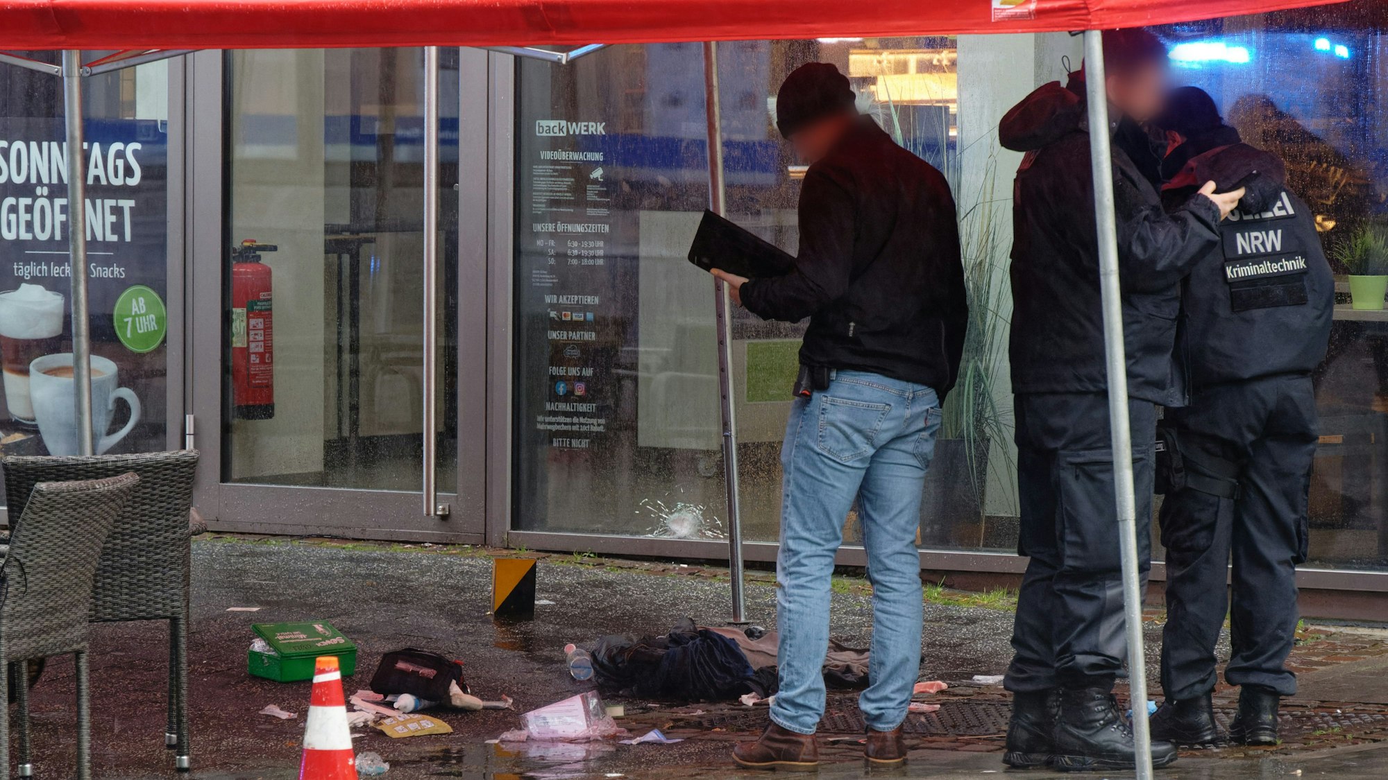 Polizeibeamte untersuchen unter einem Zeltdach den Tatort in der Innenstadt. Nach Schüssen mit mehreren Verletzten hat die Polizei den Tatort weiträumig abgesperrt. Ein Polizist habe mit seiner Dienstwaffe geschossen und damit mindestens einen Menschen verletzt, berichteten Polizeisprecher.