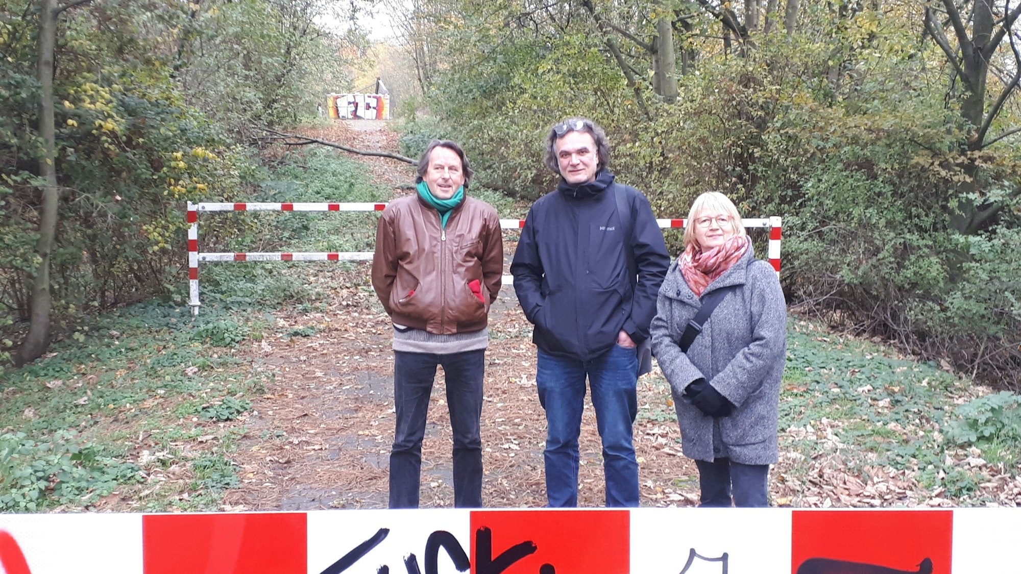 Drei Menschen stehen auf einem Waldweg.