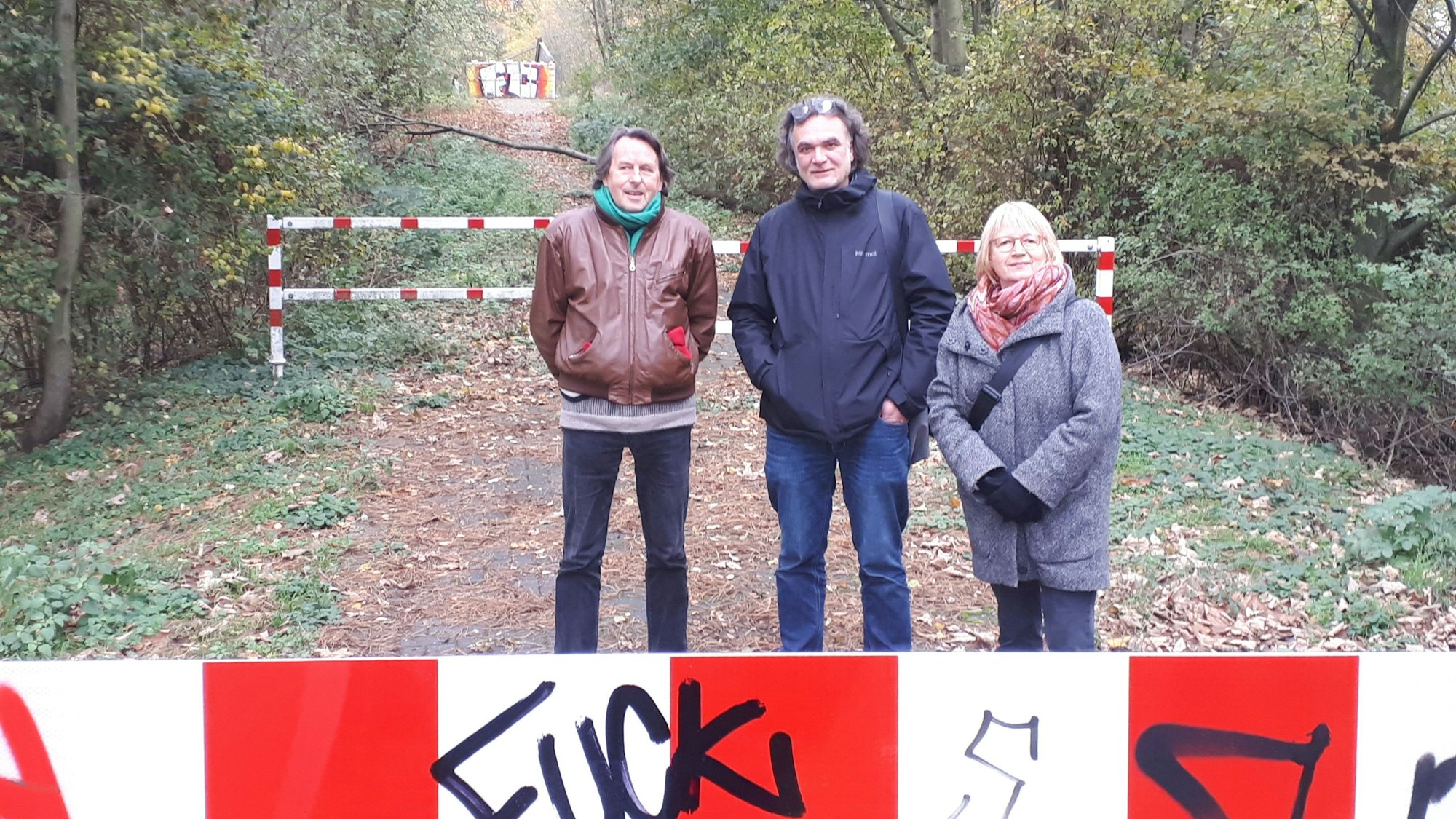 Drei Leute stehen vor einer Brücke.
