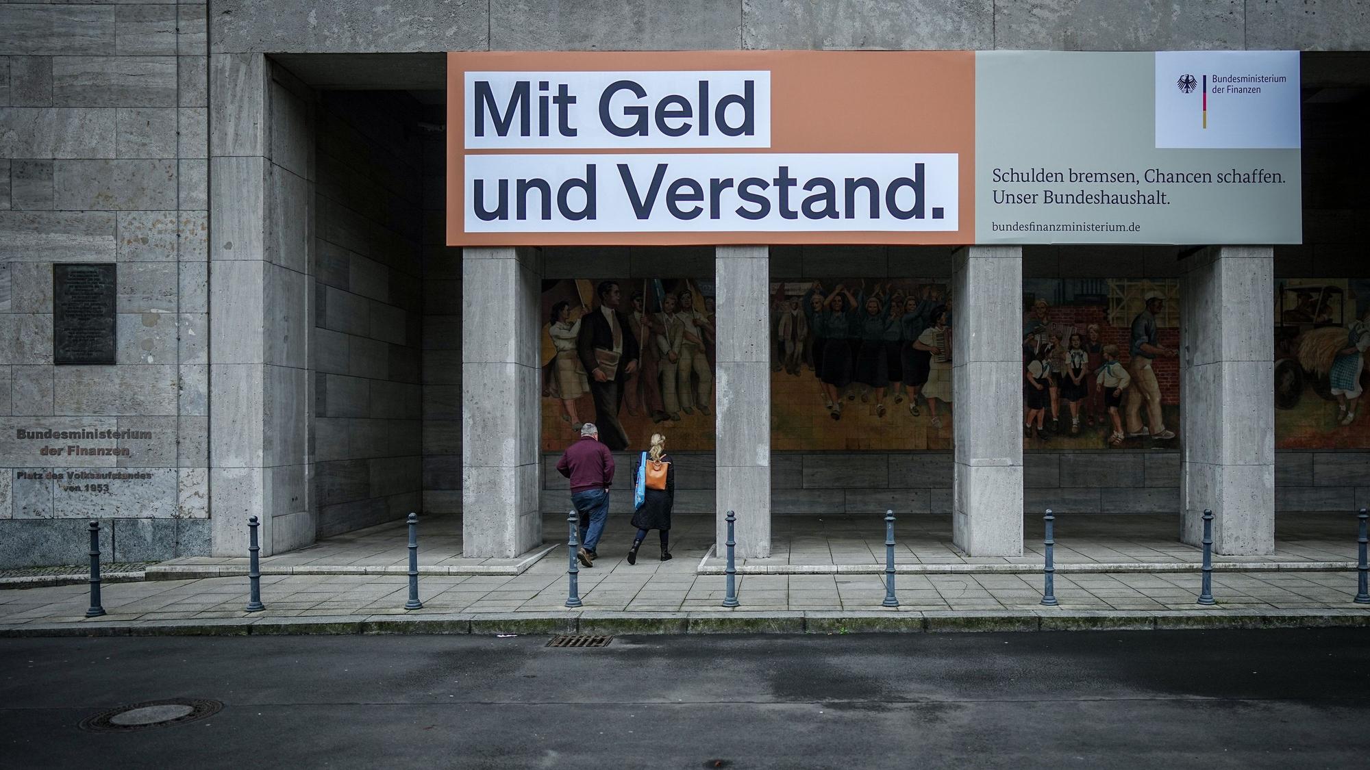 Ein Plakat mit der Aufschrift „Mit Geld und Verstand. Schulden bremsen, Chancen schaffen. Unser Bundeshaushalt.“ hängt über dem Eingang zum Bundesministerium der Finanzen.