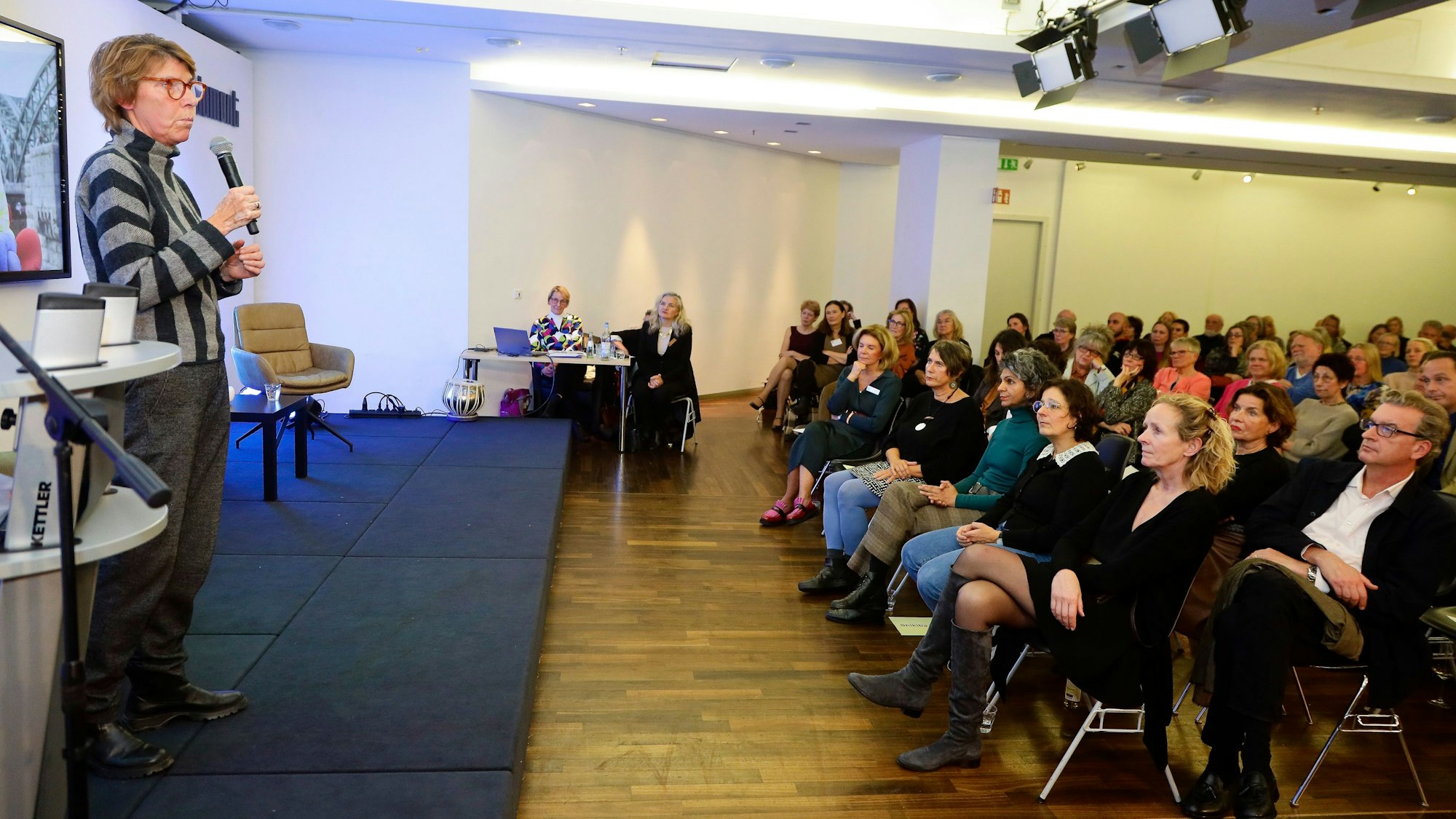Auf der Bühne der Benefizveranstaltung des Zonta Club Köln spricht Schirmherrin Bettina Böttinger. In der ersten Reihe: Isabella Neven DuMont, Isabel Ahayani, AutorinShikiba Babori und Dr. Monika Hauser.