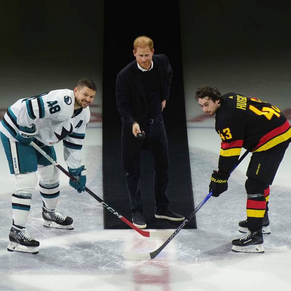 Prinz Harry (Mitte) wirft den Puck zu Tomas Hertl (links) von den San Jose Sharks und Quinn Hughes (rechts) von den Vancouver Canucks während eines feierlichen Eröffnungsspiels vor einem NHL-Eishockeyspiel in Vancouver, British Columbia.