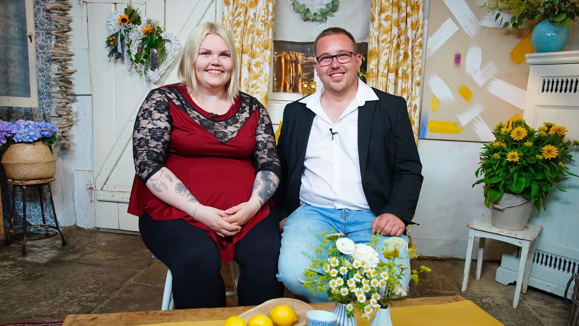 Bauer Stephan und Kandidatin Lisa sitzen nebeneinander und lächeln in die Kamera.