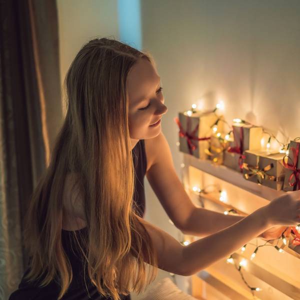 Ein jugendliches Mädchen betrachtet glücklich einen Adventskalender.