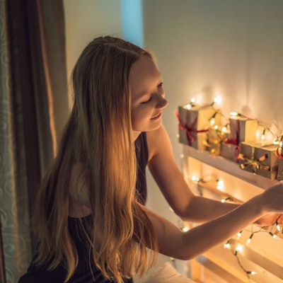 Ein jugendliches Mädchen betrachtet glücklich einen Adventskalender.