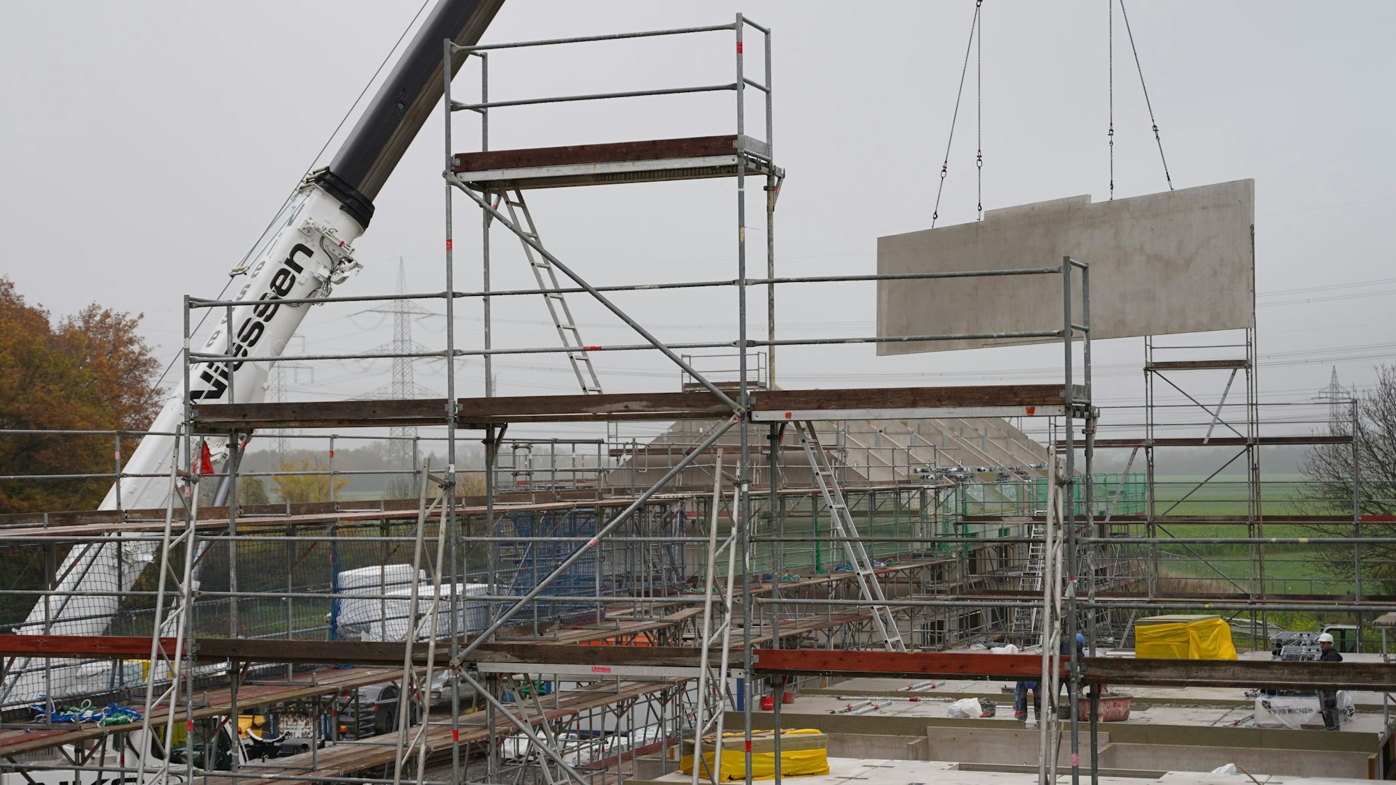 Ein Kran hebt einen Betonklotz an seinen Platz.