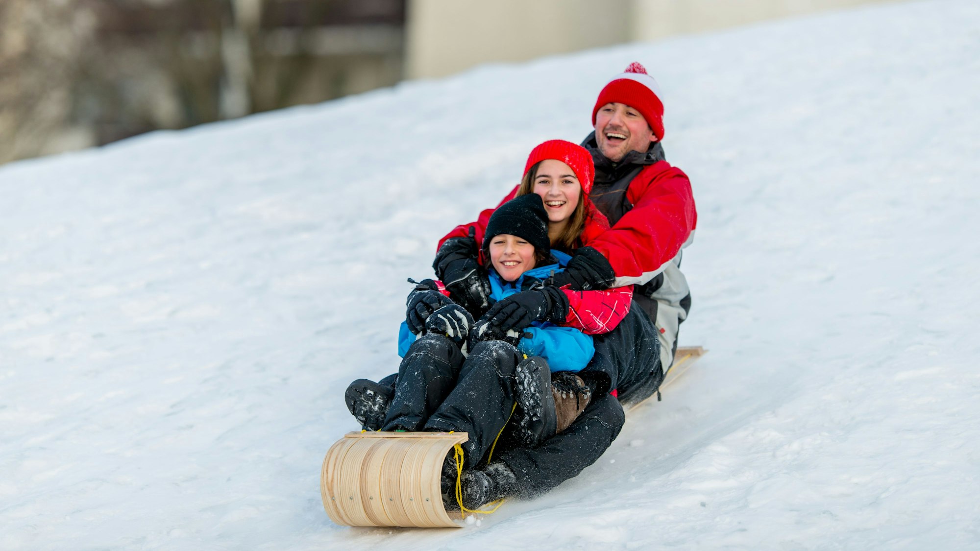 Drei Personen rodeln den Hang hinunter.