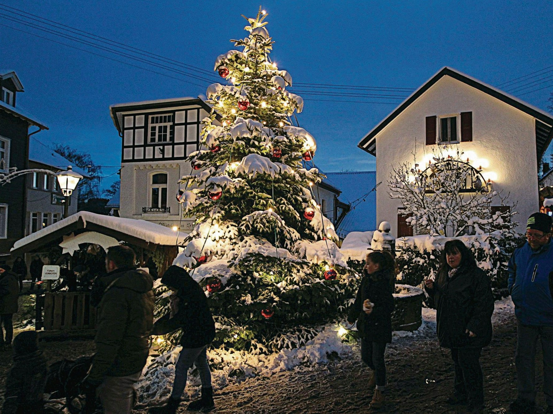 Fachwerkhäuser, Tannenbaum und Stände im Schnee.