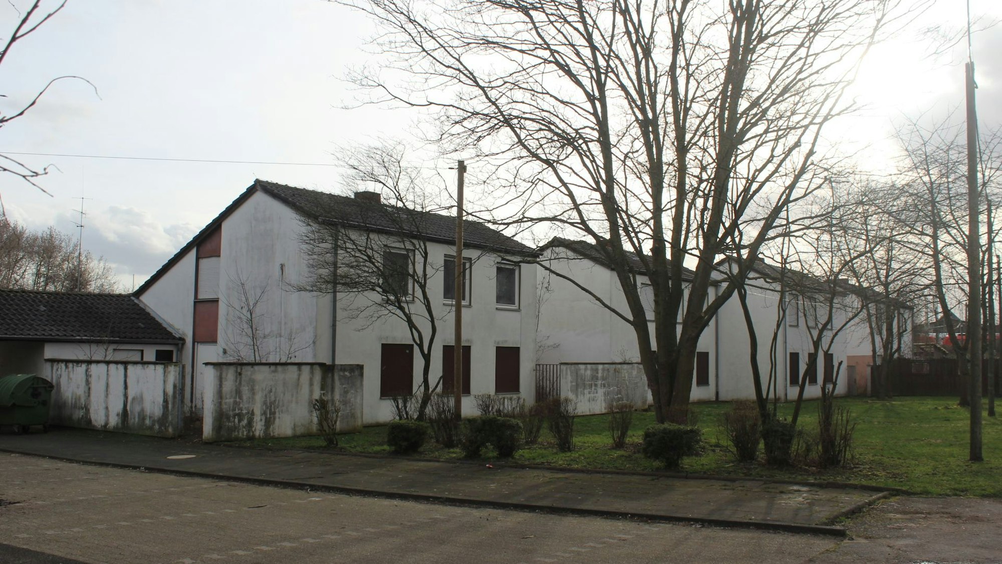 Mehrere zweigeschossige Häuser stehen an einer Wiese.