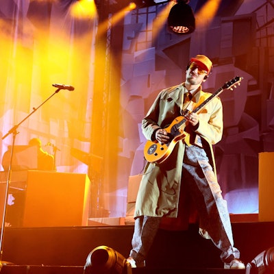 Alligatoah steht auf der Bühne und spielt Gitarre.