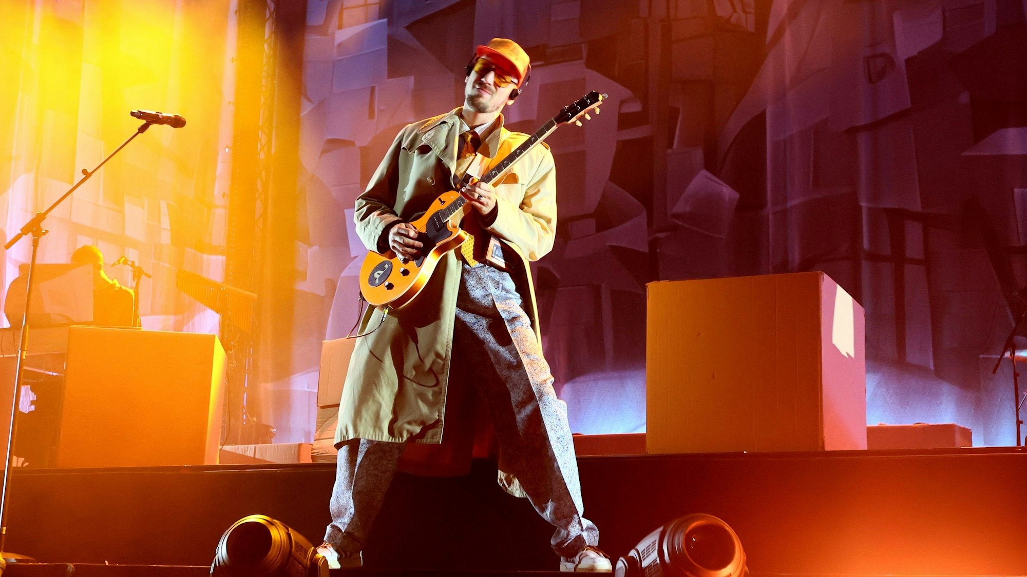 Alligatoah kam im Trenchcoat und mit oranger Kappe am 20. November 2023 auf die Bühne der Lanxess-Arena.