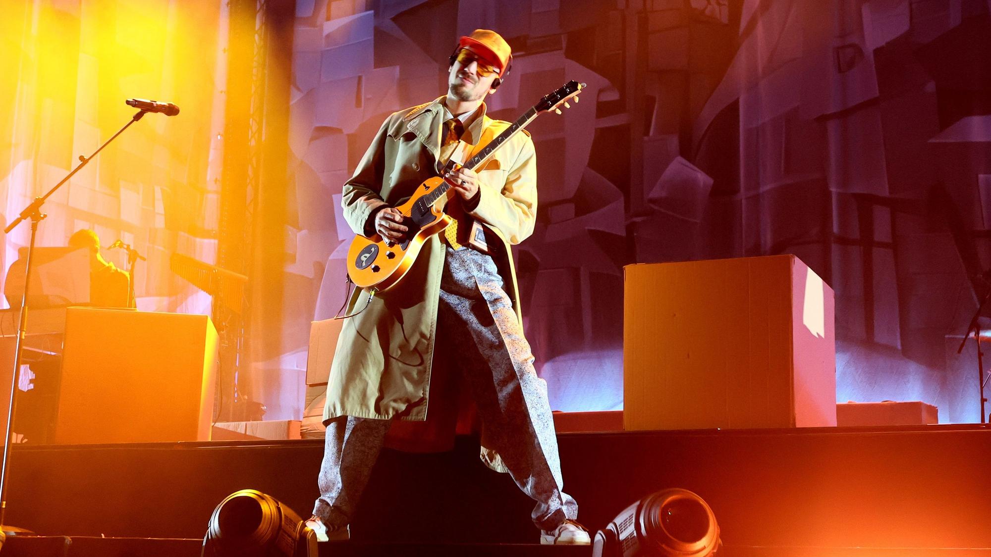 Alligatoah steht auf der Bühne und spielt Gitarre.