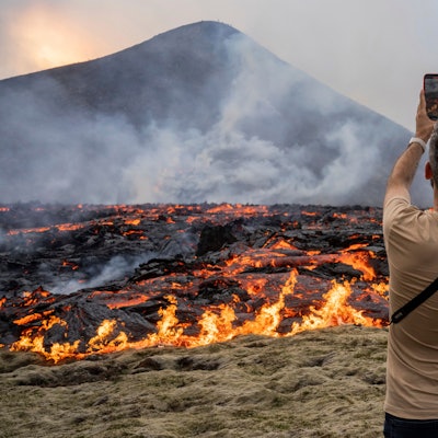 10.07.2023, Island, Fagradalsfjall: Ein Mann fotografiert, wie Lava aus einer Spalte eines Vulkans in der Nähe des Berges Litli-Hrútur, etwa 30 Kilometer südwestlich von Reykjavik, austritt. Auf Island ist es im dritten Jahr in Folge zu einem vulkanischen Ausbruch gekommen. Störungen des Flugverkehrs seien nicht zu befürchten, teilte die isländische Regierung mit. Foto: Marco Di Marco/AP/dpa +++ dpa-Bildfunk +++