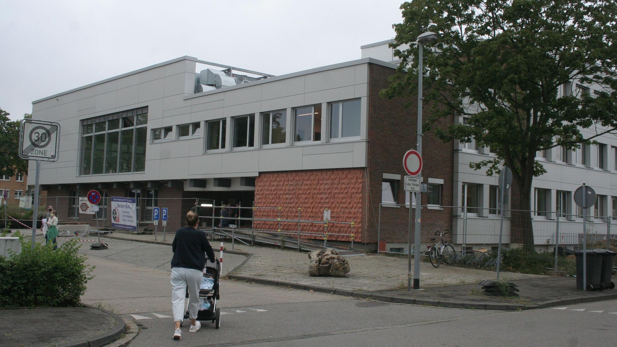Eine Frau schiebt einen Kinderwagen in Richtung des Bedburger Rathauses in Kaster.
