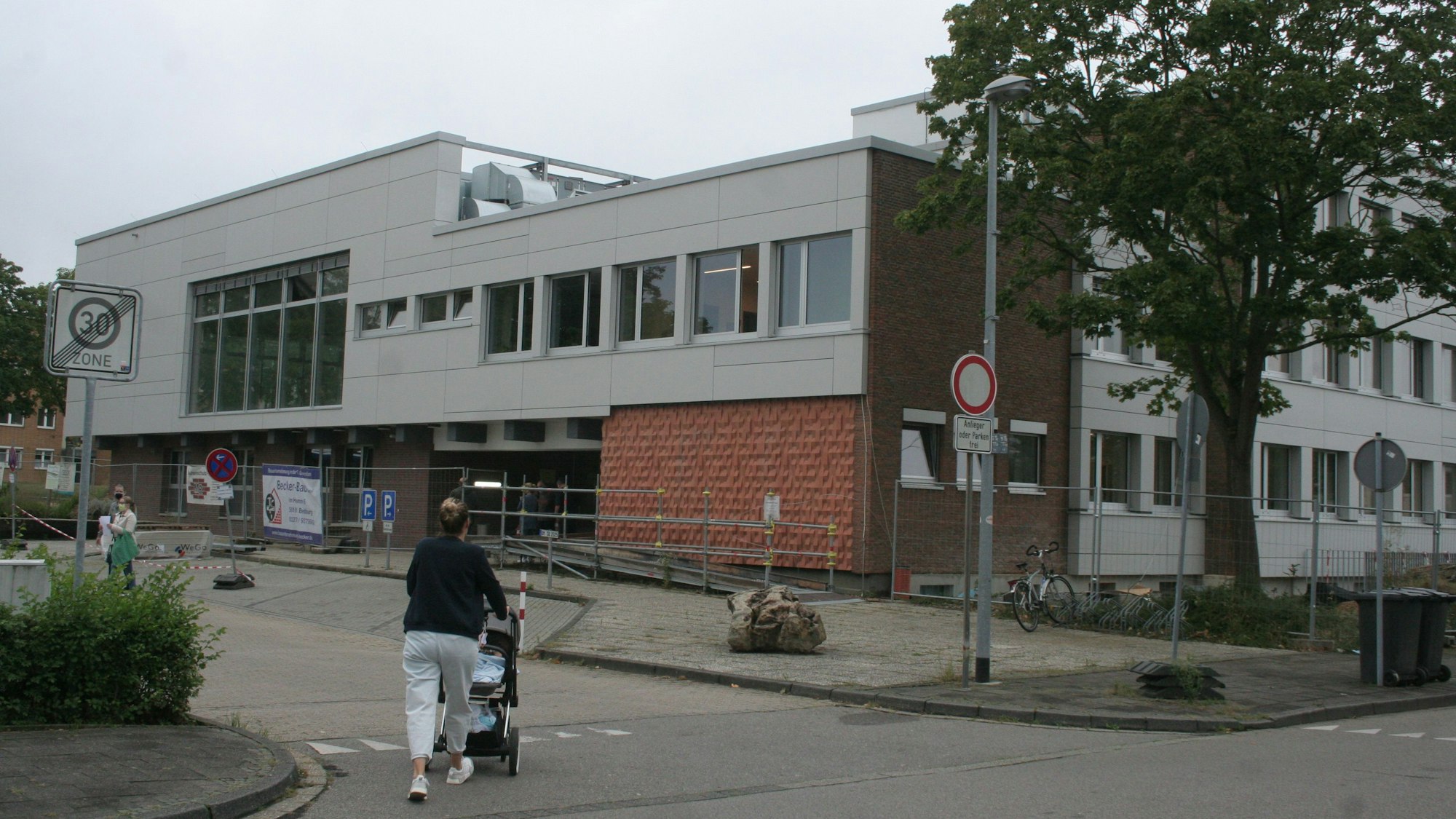 Eine Frau schiebt einen Kinderwagen in Richtung des Bedburger Rathauses in Kaster.