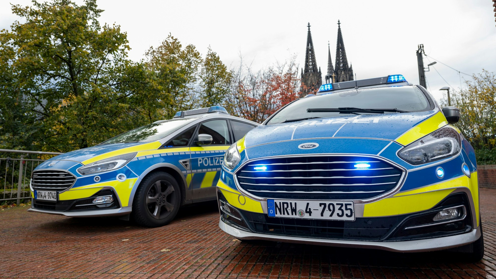 Das Foto zeigt zwei Einsatzfahrzeuge der Polizei vor dem Kölner Dom.