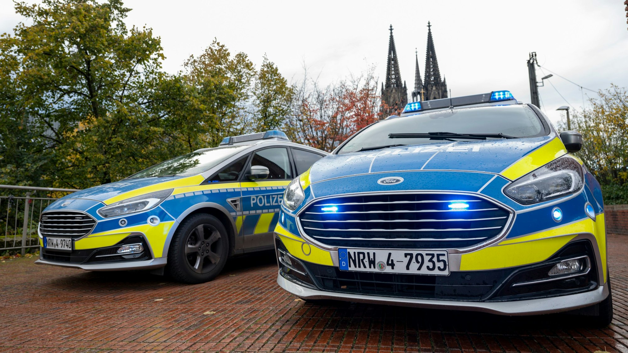 Das Foto zeigt zwei Polizeiwagen vor dem Kölner Dom.