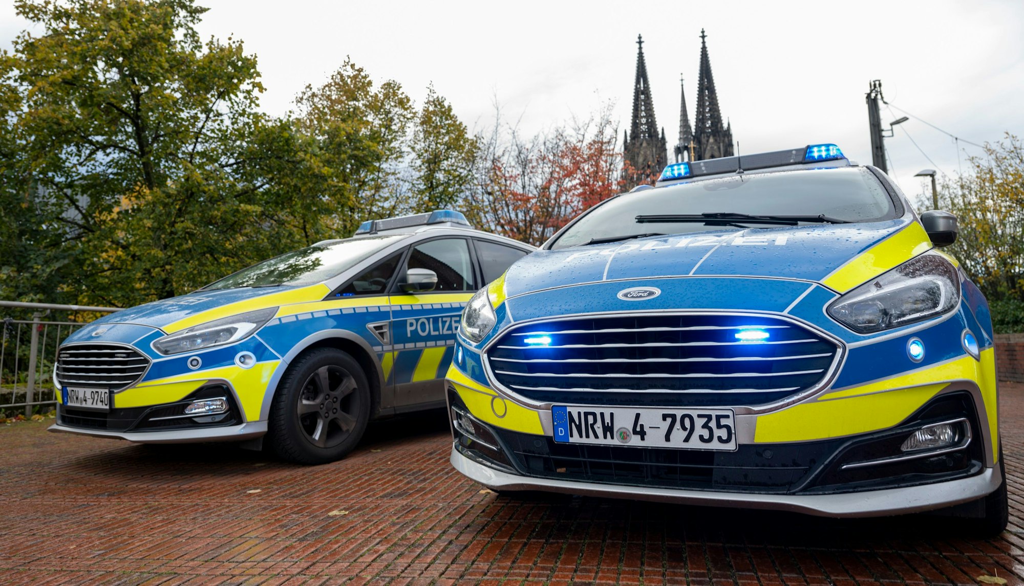 Zwei Streifenwagen stehen nebeneinander, im Hintergrund ist der Kölner Dom zu sehen