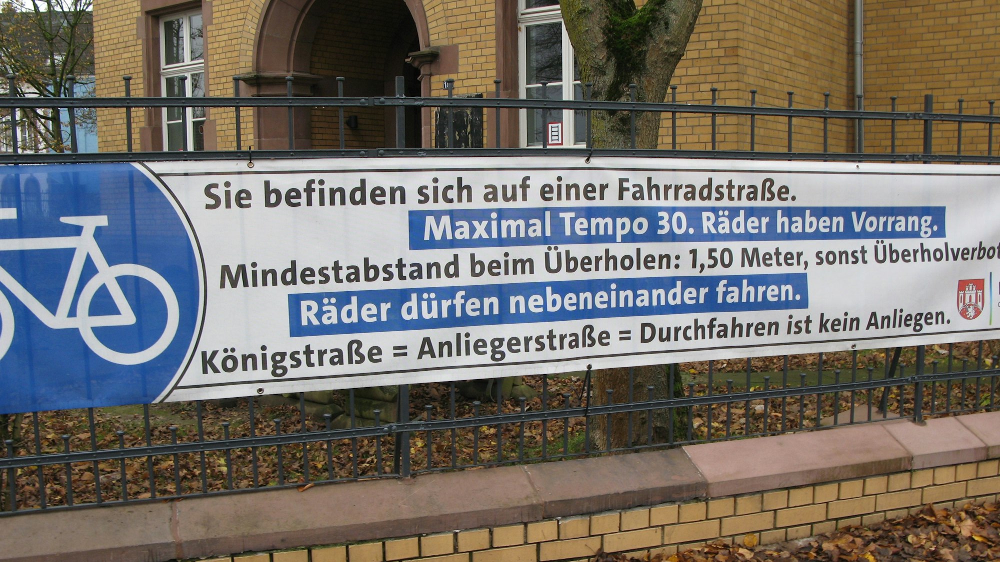 Ein Transparent hängt an einem Zaun, es informiert darüber, dass die Königstraße in Hennef jetzt eine Fahrradstraße ist und nur noch Anlieger mit dem Auto durchfahren dürfen.
