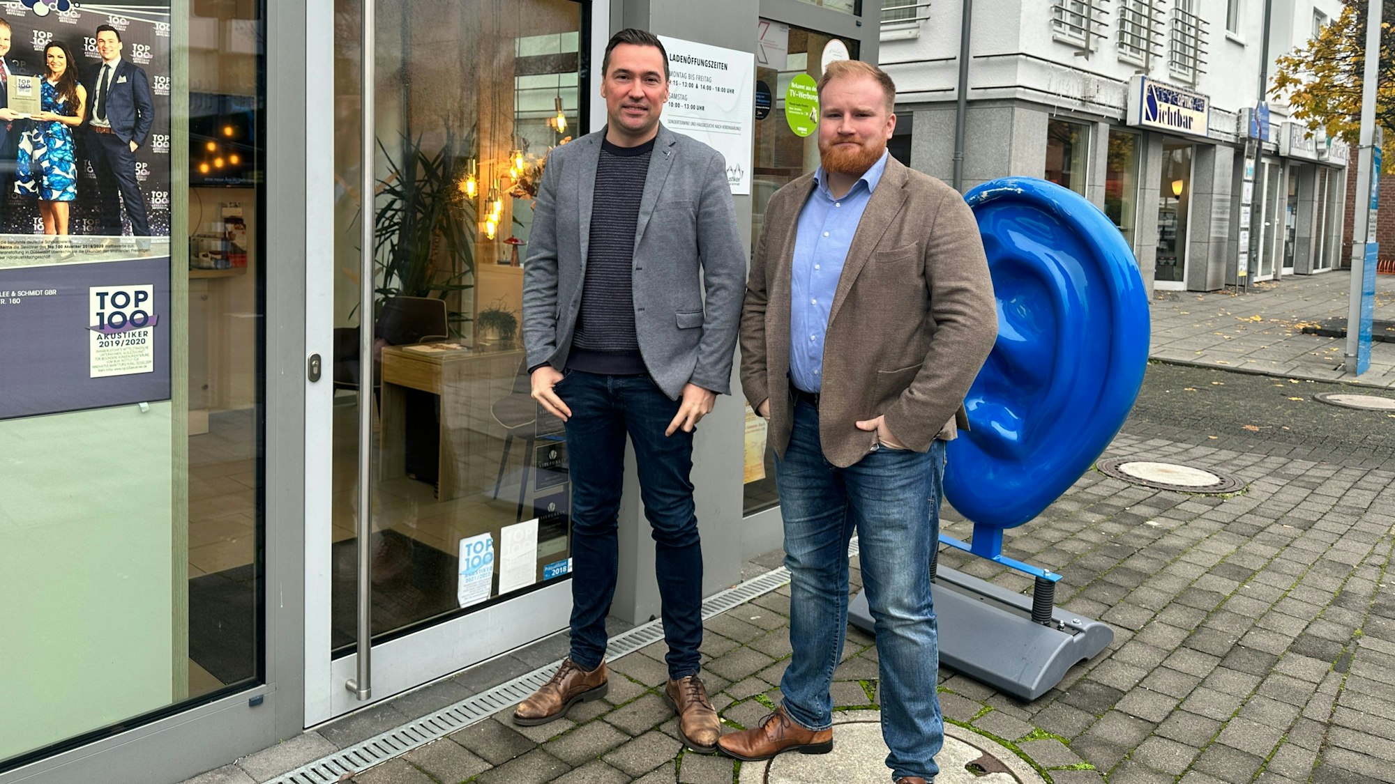 Zwei Männer stehen vor einem Geschäft.