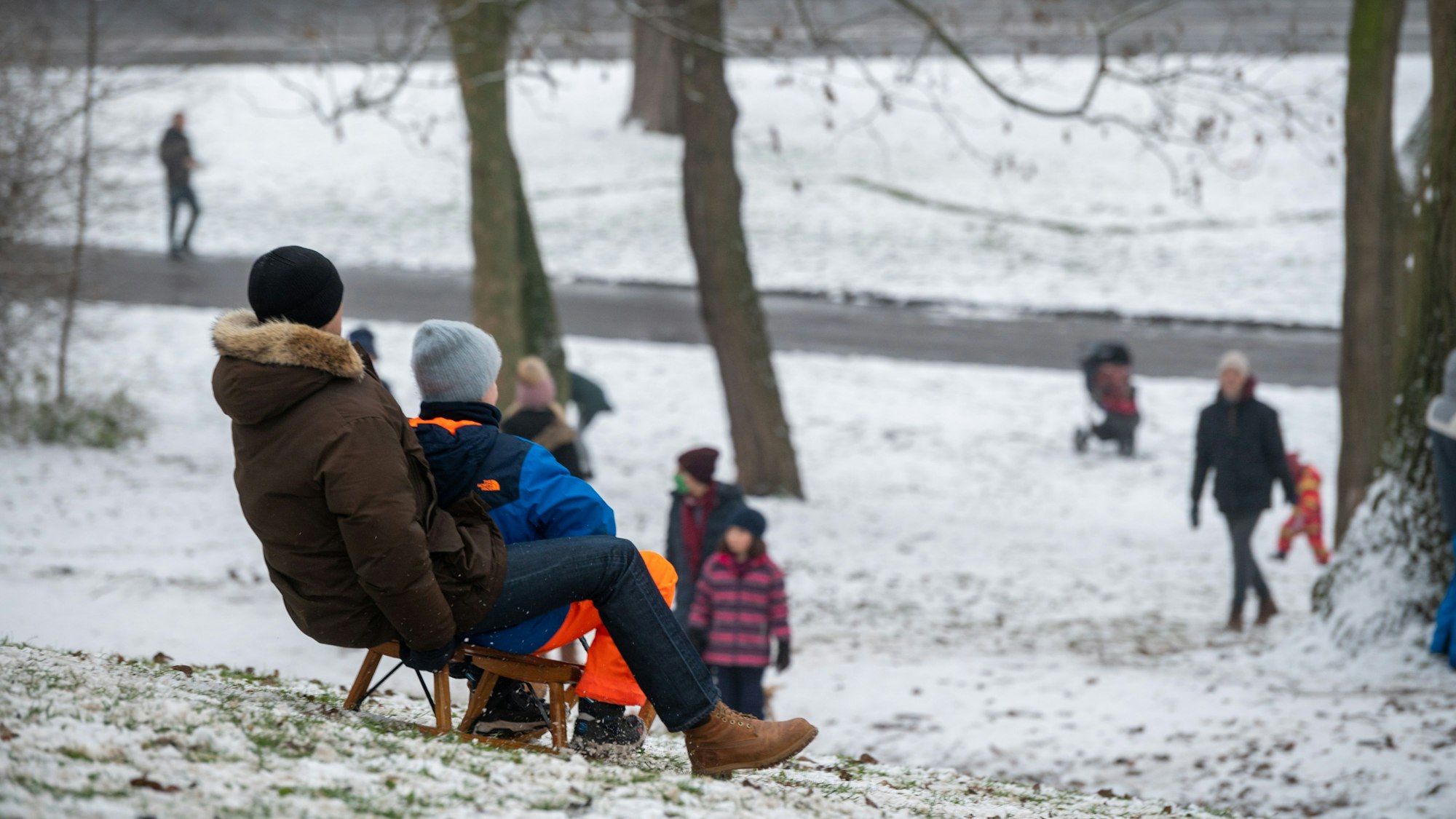 Kinder fahren Schlitten am Aachener Weiher.