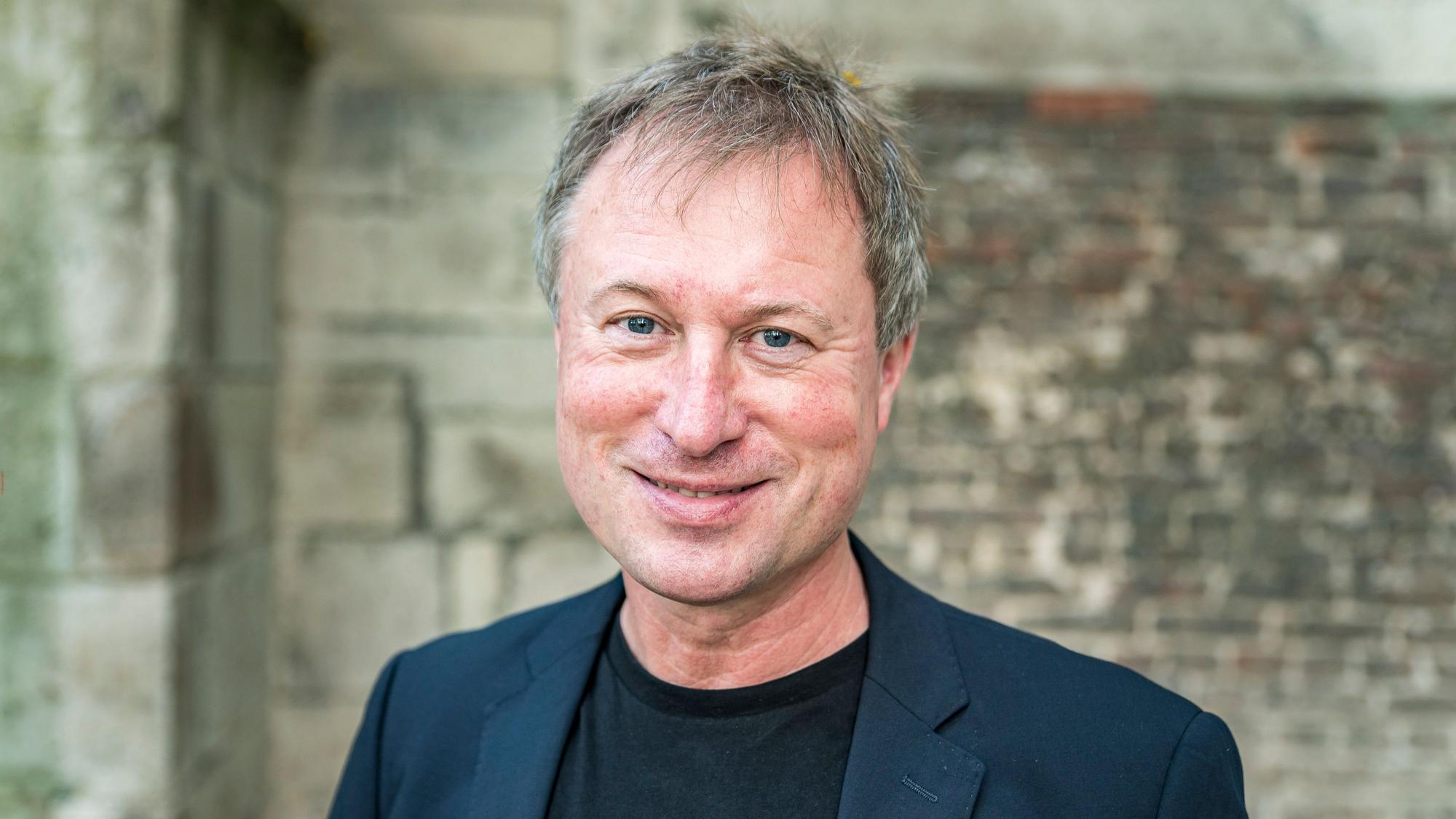 Stefan Kraus steht vor einer Mauer im Innenhof von Kolumba.