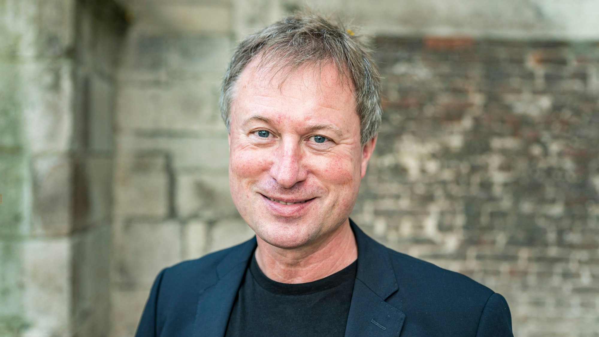 Stefan Kraus steht vor einer Mauer im Innenhof von Kolumba.