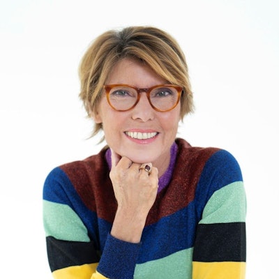 Das Bild zeigt Bettina Böttinger. Die Moderatorin stützt ihr Kinn mit der Hand. Sie trägt eine Brille und einen bunt-gestreiften Pullover.