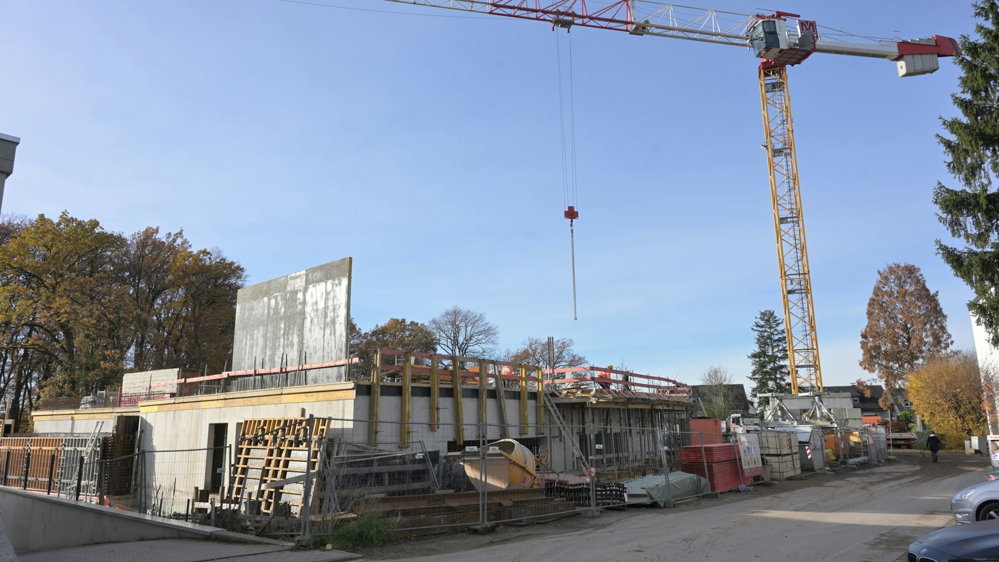 Der Rohbau des Erdgeschosses des neuen Schulgebäudes sowie Arbeitsmaterialien und ein gelber Baukran sind zu sehen.