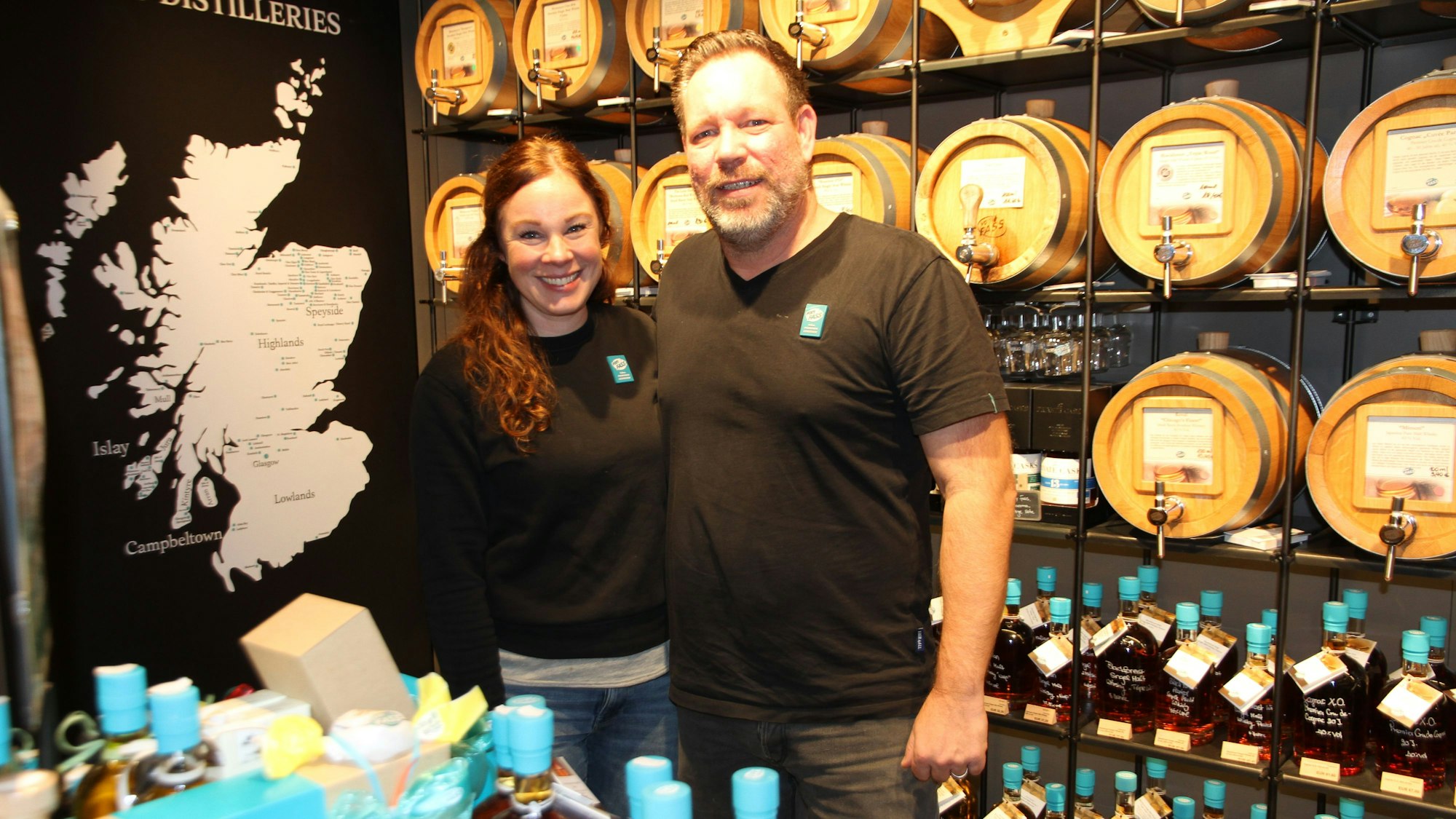 Eine Frau und ein Mann vor Regalen mit Fässern und Flaschen