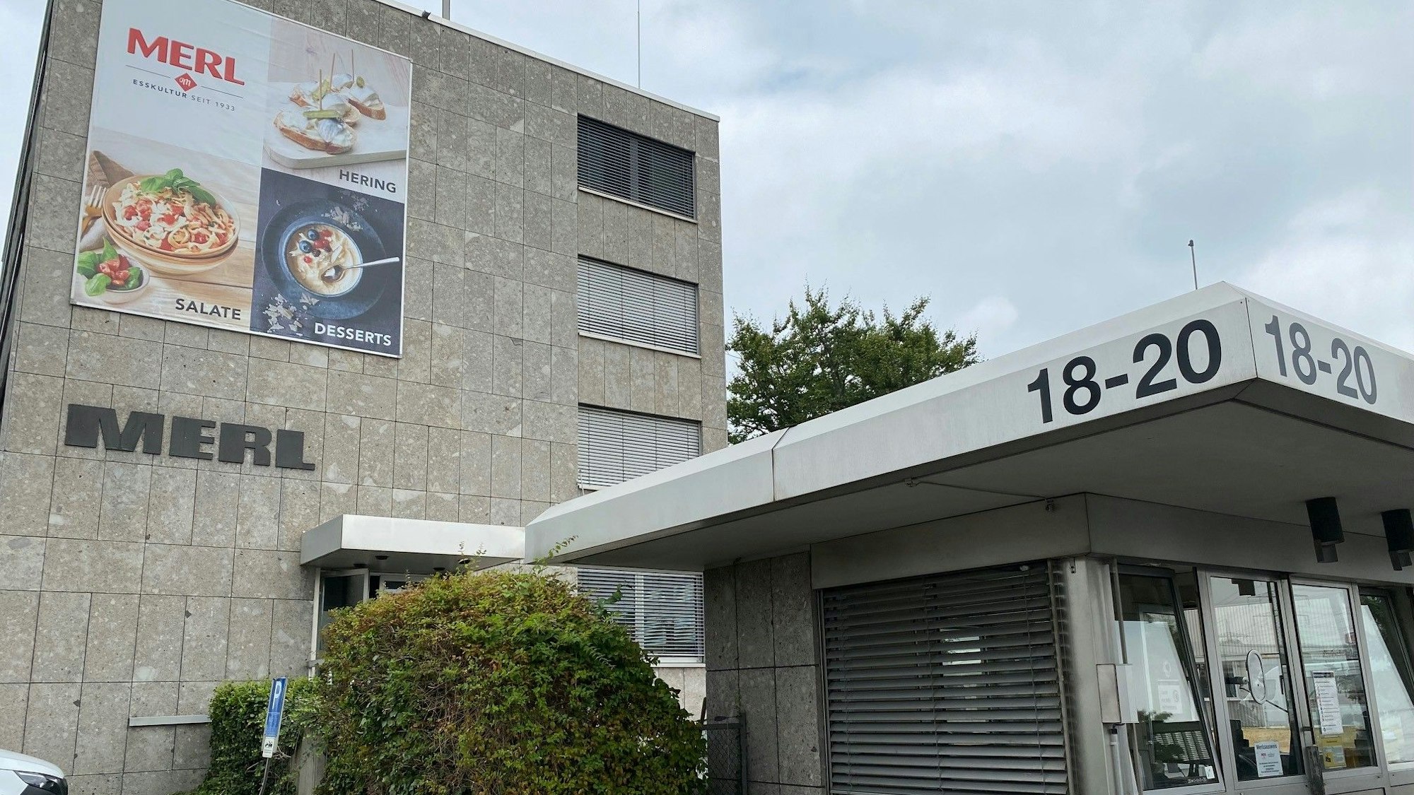 Der Hauptsitz des Feinkostherstellers Merl mit einem Pförtnerhäuschen vor dem Gebäude von außen.