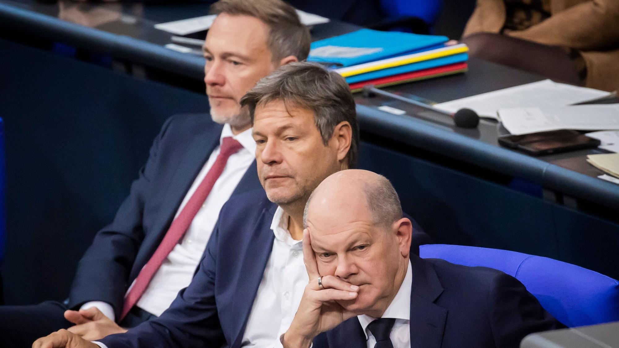 Bundeskanzler Olaf Scholz (SPD, r-l), Robert Habeck (Bündnis 90/Die Grünen), Bundesminister für Wirtschaft und Klimaschutz, und Christian Lindner (FDP), Bundesminister der Finanzen, sitzen im Plenum des Deutschen Bundestages und verfolgen die Debatte. (Symbolbild)