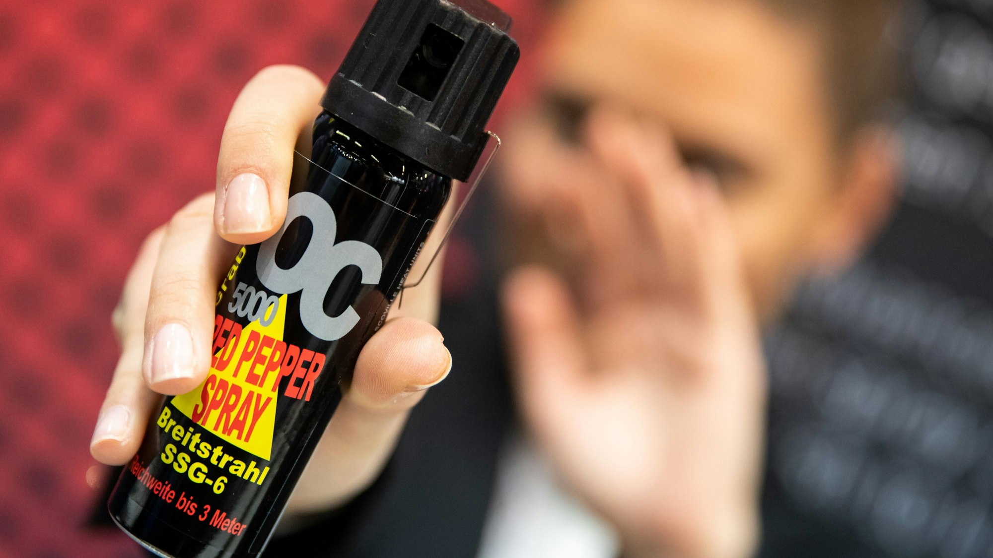 Eine Frau hält auf der Fachmesse für Jagd, Schießsport, Outdoor und Sicherheit Pfefferspray in der Hand.