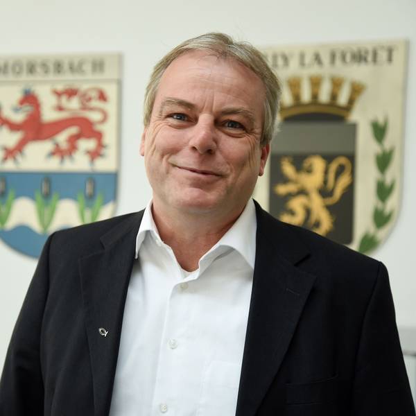 Zum 1. April übernimmt Oliver Moritz die Leitung der Morsbacher Entwicklungsgesellschaft als hauptamtlicher Geschäftsführer. Dort arbeitet er indes schon seit diesem Oktober. Unser Bild zeigt ihm in Ratssaal vor dem Morsbacher Wappen und dem der Partnergemeinde Milly-la-Forêt (rechts).