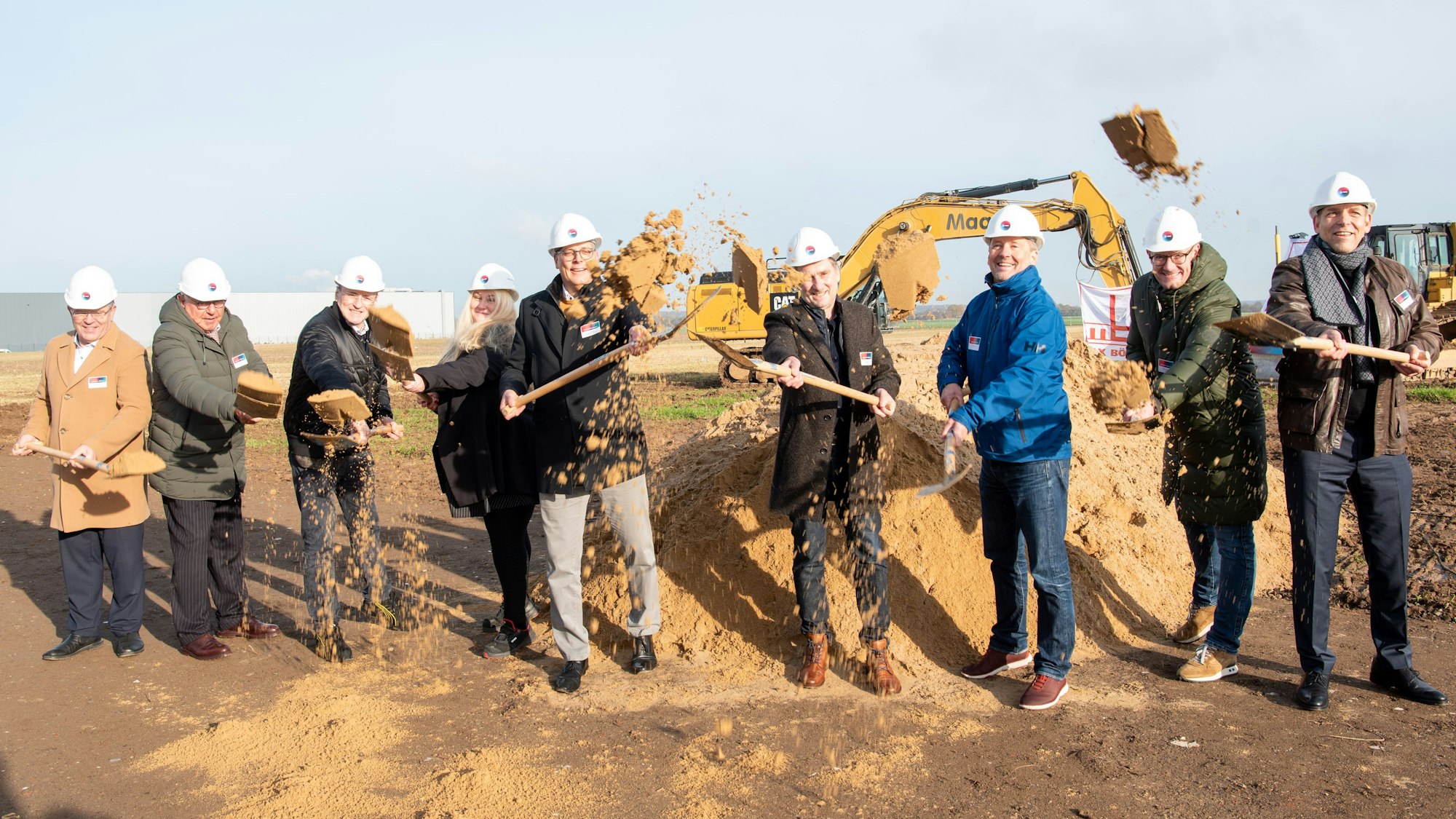 Mehrere Männer und eine Frau schaufeln mit Spaten losen Sand und werfen ihn in die Höhe. In der Mitte steht Ulf Hürtgen, Bürgermeister der Stadt Zülpich.